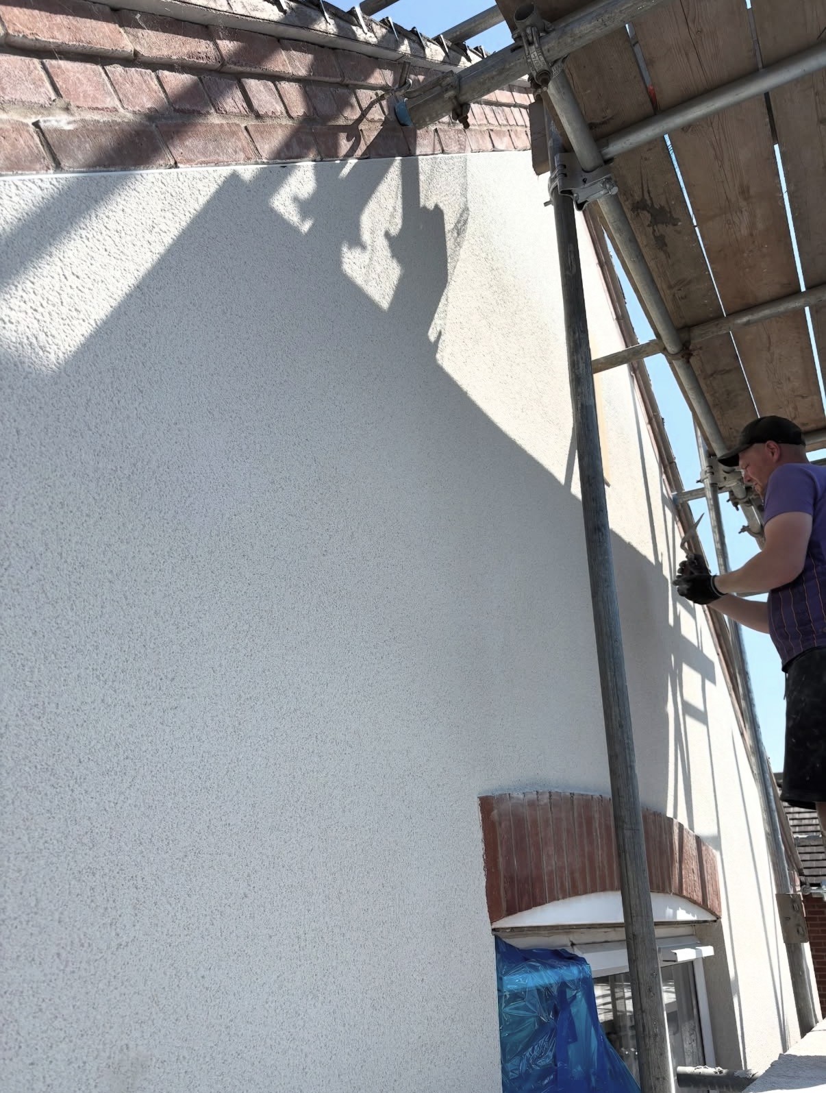 Freshly rendered gable end wall of a house with scaffolding